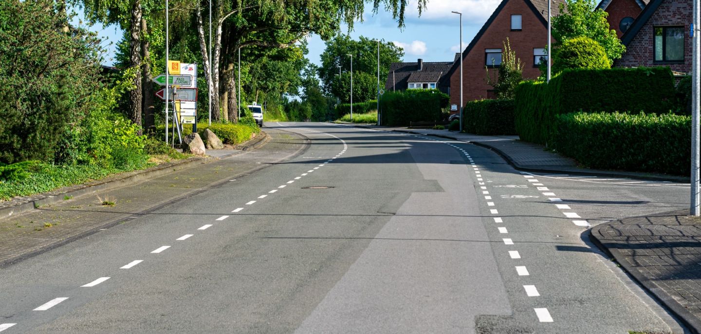 Ruhige Wohnstraße mit Einfamilienhäusern, Hecken und Bäumen in Nordrhein-Westfalen.